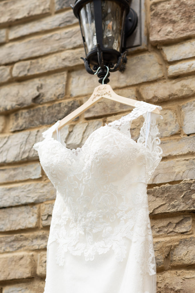 close up of wedding dress hanging on a bride hanger on a brick wall